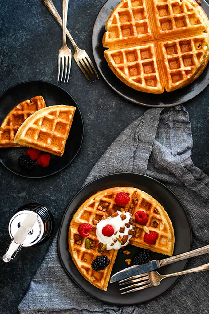 An overhead view of three plates, each with a Yogurt Waffle resting on top.