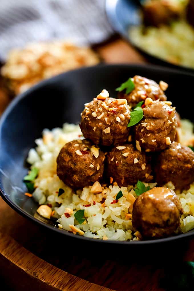 A bowl of Slow Cooker Thai Chili Peanut Meatballs garnished with chopped peanuts and cilantro.