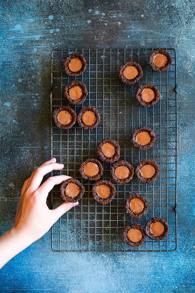 Peanut Butter Cup Brownie Bites on a wire rack with a hand reaching for one.