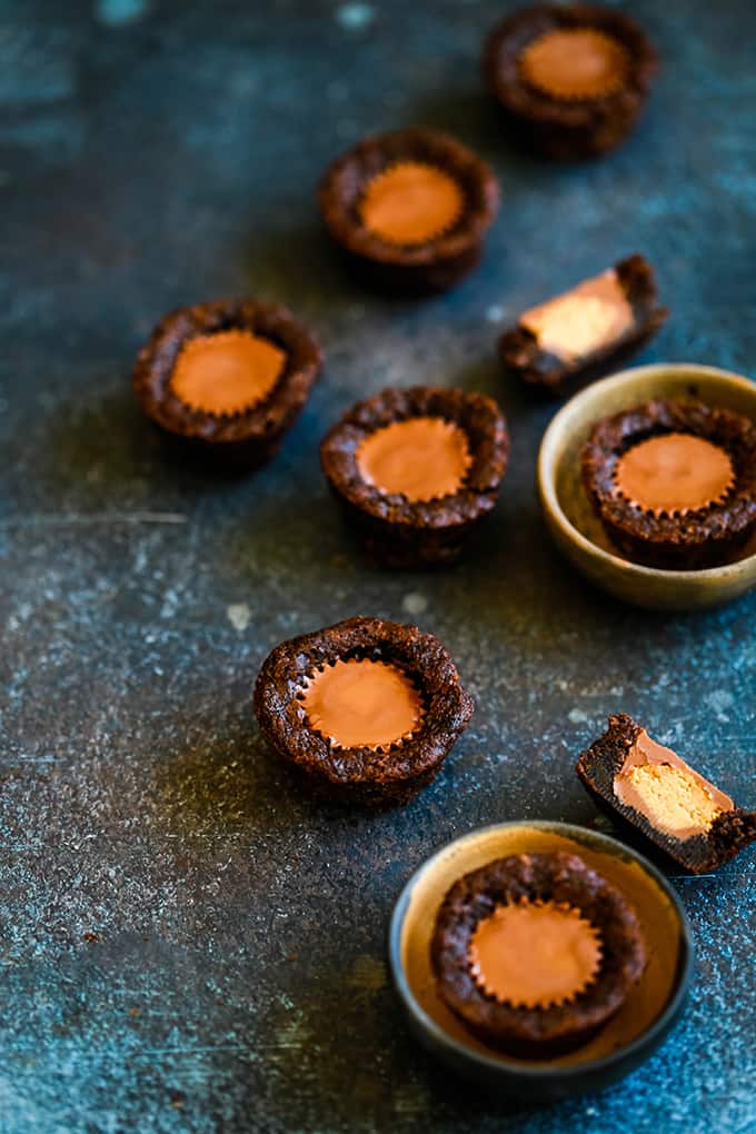 Peanut Butter Cup Brownie Bites on a blue surface and two in small bowls.