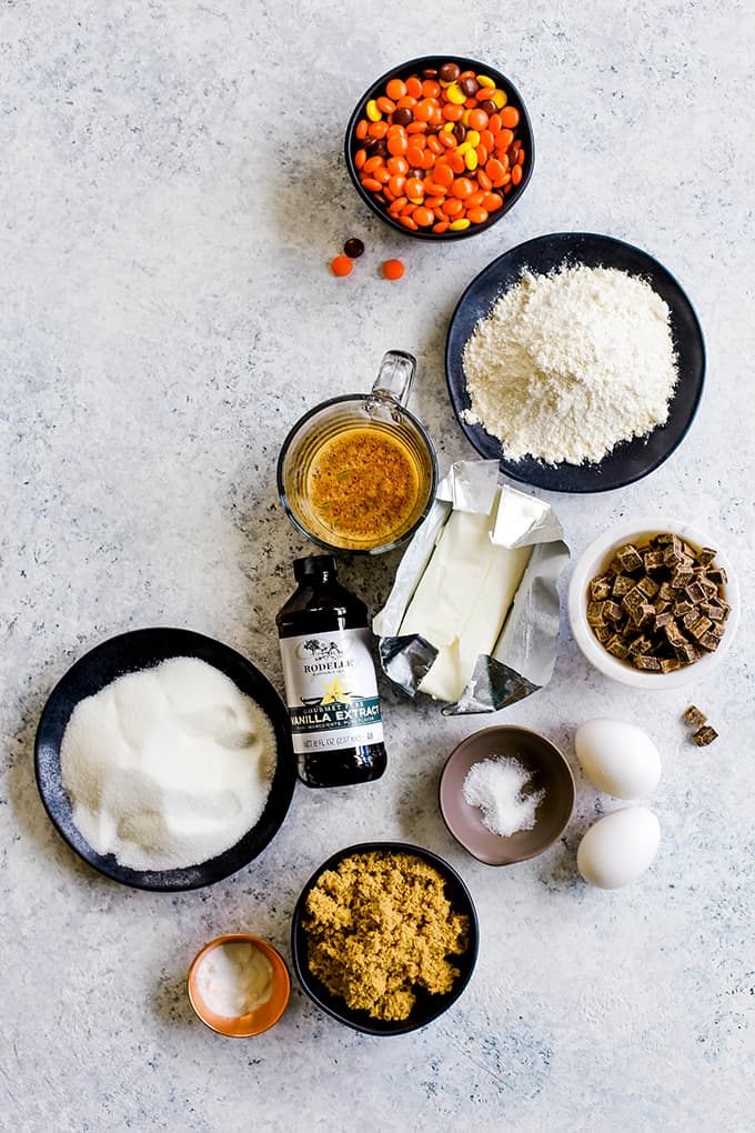 The ingredients needed for Reese's Pieces Chocolate Chip Cookies on a white background.