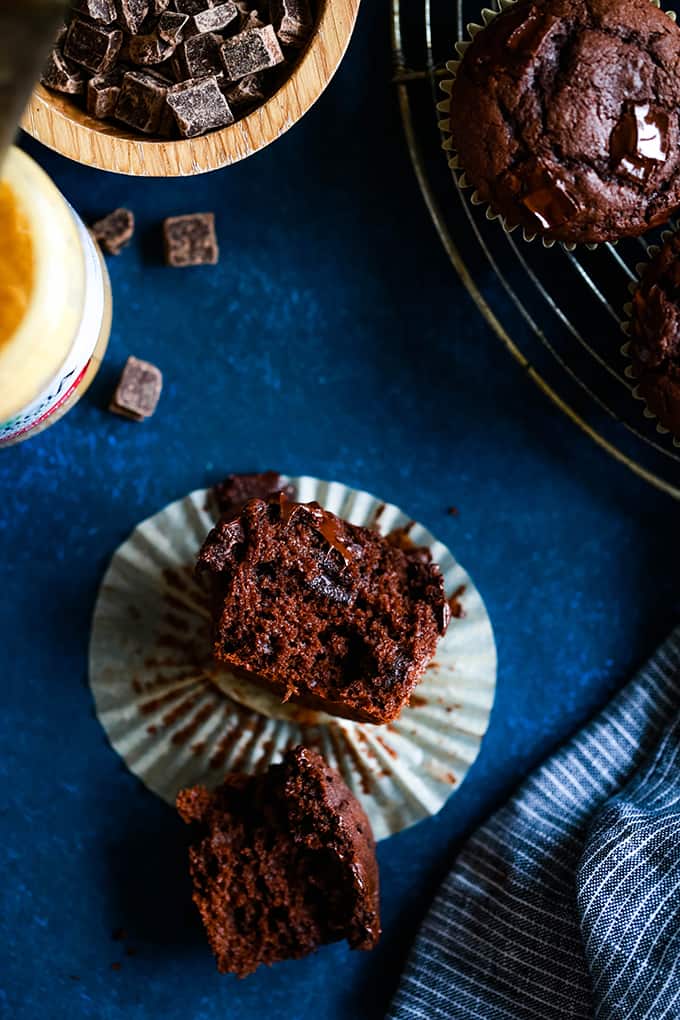 A Peanut Butter Mocha Chocolate Chip Muffin is split in half and rests on a blue surface.