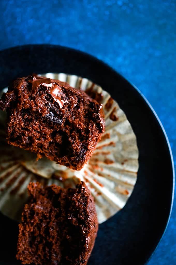 A Peanut Butter Mocha Chocolate Chip Muffin is split in half on a black plate.