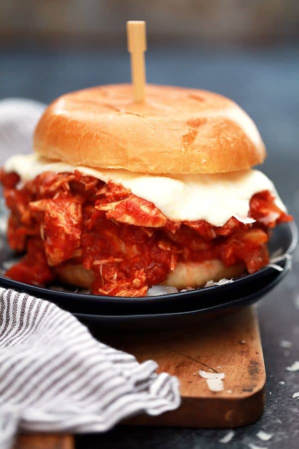 These Slow Cooker Chicken Parmesan Sandwiches take just 10 minutes to prepare and are the definition of true comfort food. A hearty tomato sauce imparts it's amazing flavor to the chicken while ooey, gooey, melty cheese is the perfect finishing touch.