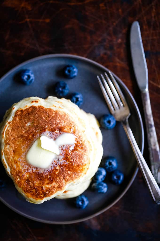 An overhead view of a stack of the Best Buttermilk Pancakes topped with a melting pat of butter.