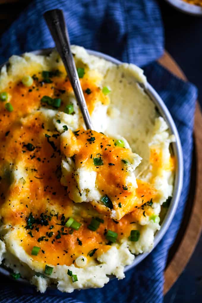 A spoon of potatoes sits on a bowl full of make ahead Aunt Ruthie Mashed Potatoes.