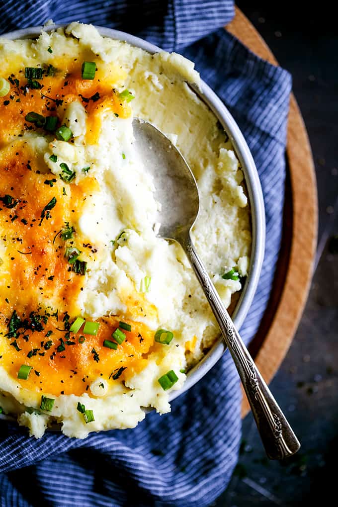 A serving spoon rests inside a bowl full of Aunt Ruthie Mashed Potatoes.