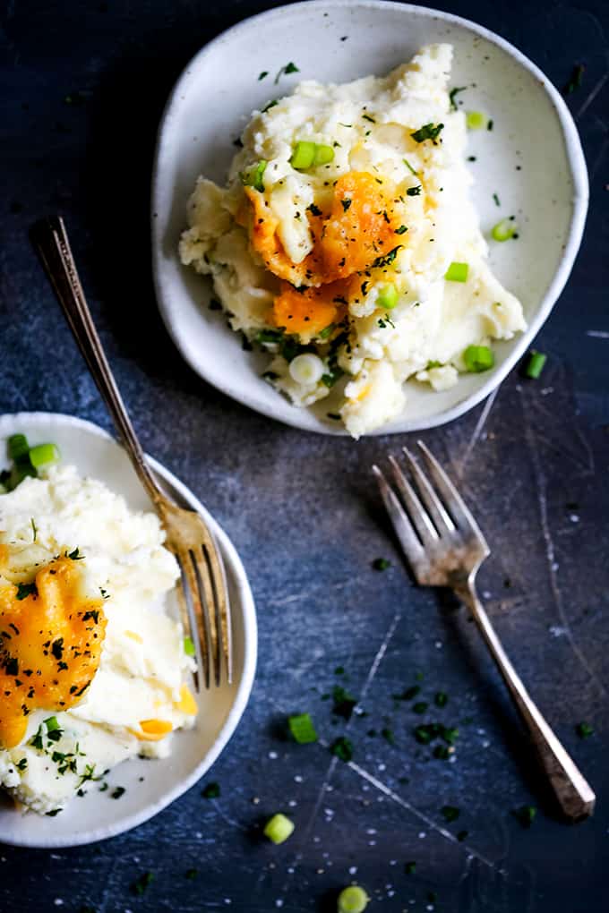 Two white plates with servings of make ahead Aunt Ruthie Mashed Potatoes and forks.