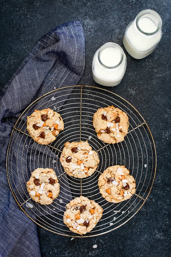 An overhead view of Magic Cookie Bar Cookies on a wire rack flanked by a napkin and two bottles of milk.