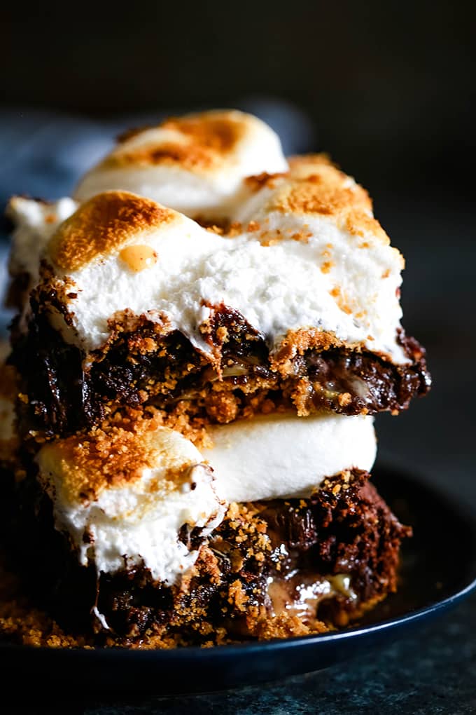 Two Dulce de Leche Swirl S'mores Brownies are stacked on top of each other on a black plate.