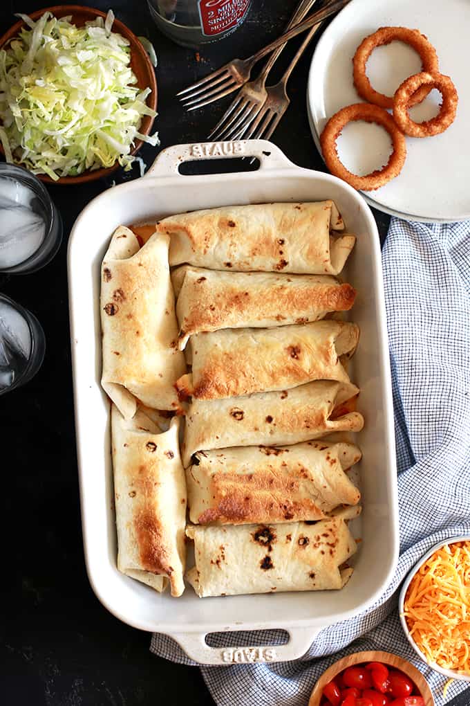 These crispy Cheeseburger Chimichangas will have your eyes thinking Mexican food but the taste is all-American!  Ground beef spiked with ketchup and mustard along with all of your favorite burger toppings are rolled into a flour tortilla and baked until crisp.  They're then placed on a bed of shredded lettuce before being adorned with more cheese and tomatoes and drizzled with mayonnaise.  