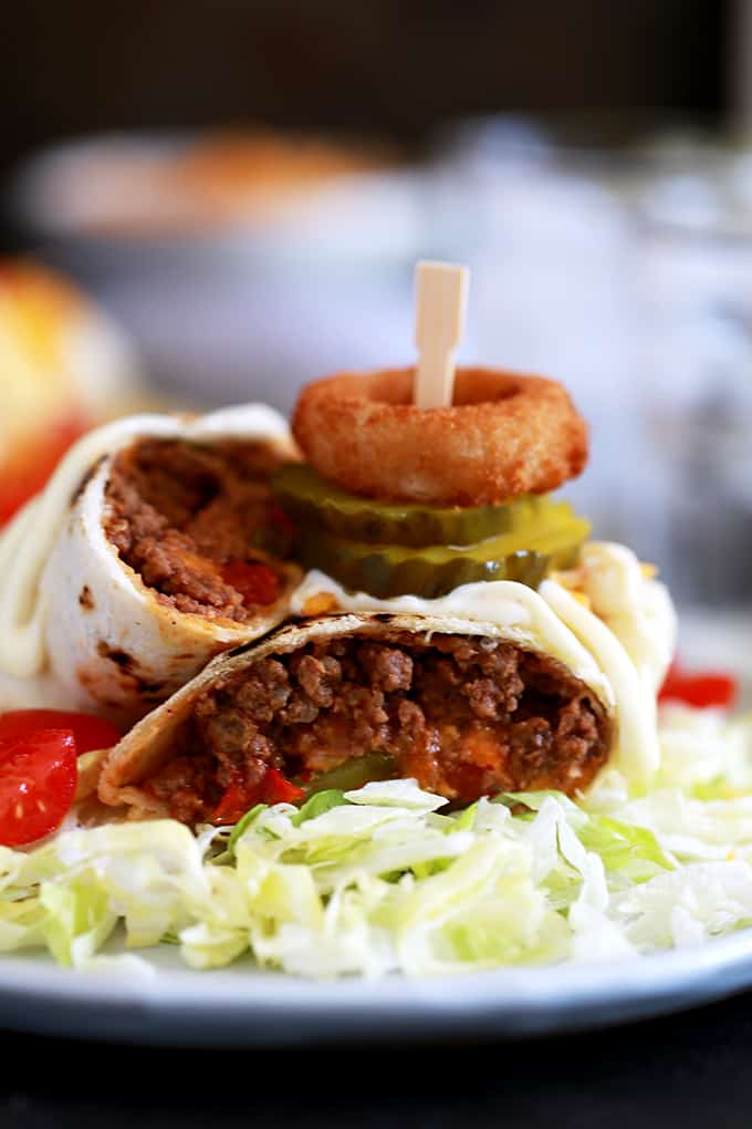 These crispy Cheeseburger Chimichangas will have your eyes thinking Mexican food but the taste is all-American!  Ground beef spiked with ketchup and mustard along with all of your favorite burger toppings are rolled into a flour tortilla and baked until crisp.  They're then placed on a bed of shredded lettuce before being adorned with more cheese and tomatoes and drizzled with mayonnaise.  