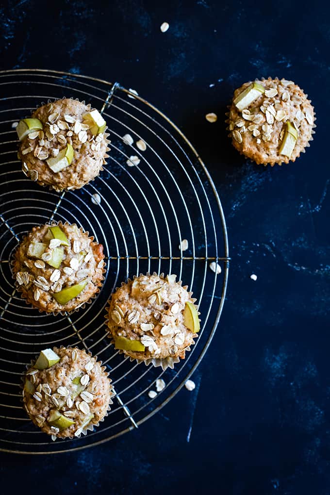 Cinnamon Apple Oatmeal Muffins on a circular wire cooling rack on a black background.