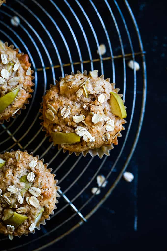 Cinnamon Apple Muffins on a circular wire cooling rack on a black background.