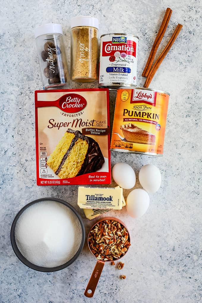 All of the ingredients needed to create Upside Down Pumpkin Pie on a white speckled background.