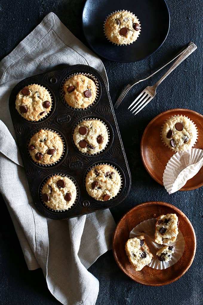 An overhead shot of Oatmeal Chocolate Chip Muffins in a muffin pan and three plates with muffins.