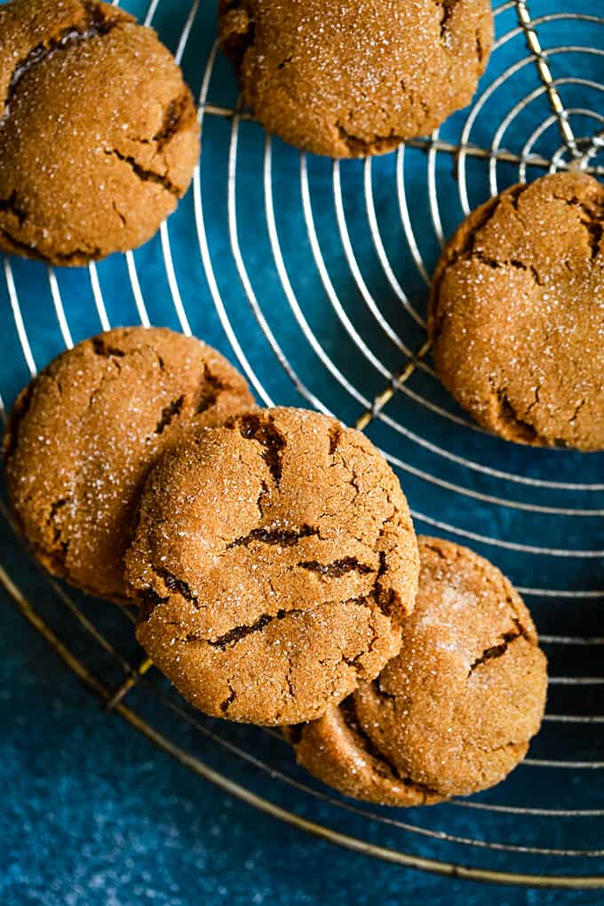 Soft and Chewy Ginger Cookies rest on a wire cooling rack sitting on a blue background.