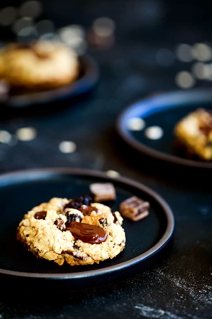 An Oatmeal Raisin Chocolate Chip Cookie on a black plate.