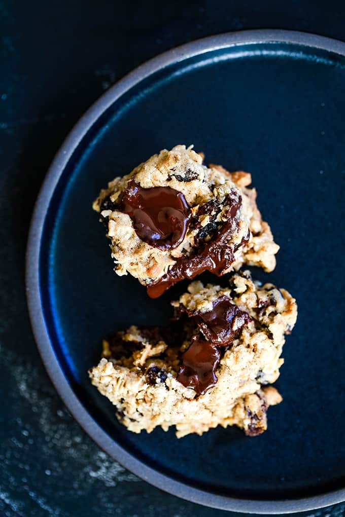 A halved Oatmeal Raisin Chocolate Chip Cookie on a black plate.