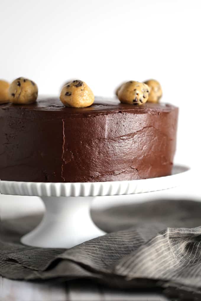 This Double Chocolate Peanut Butter Chocolate Chip Cookie Dough Cake is what peanut butter and chocolate lovers dream about. Creamy and studded with mini chocolate chips, a thick layer of peanut butter cookie dough is sandwiched between two layers of chocolate cake. The entire cake is then cloaked in a rich, whipped chocolate ganache frosting before being crowned with additional spheres of cookie dough. 