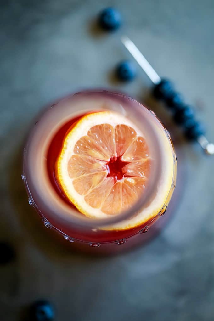 An overhead view of a slice of lemon in a pitcher of Blueberry Lemonade.