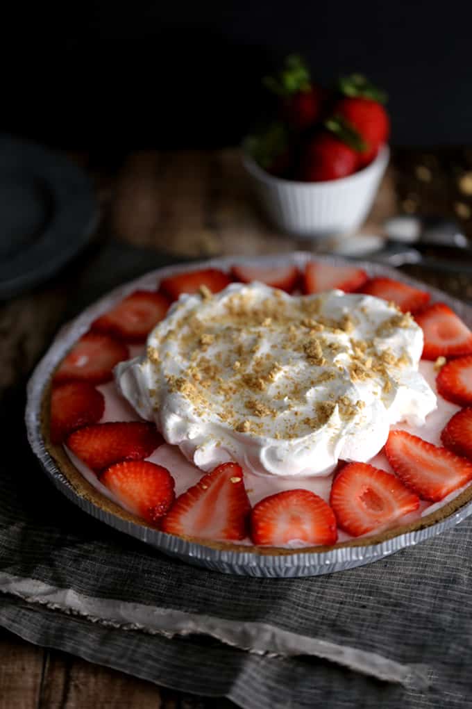 This Strawberry Cheesecake Ice Cream Pie takes just 10 minutes and five ingredients to prepare! Strawberry cheesecake ice cream is swirled together with cheesecake pudding and whipped topping before being poured into a graham cracker pie shell. It's then frozen before being garnished with slices of juicy strawberries, a pillowy cloud of additional whipped topping and a dusting of graham cracker crumbs.