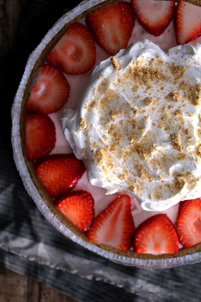 This Strawberry Cheesecake Ice Cream Pie takes just 10 minutes and five ingredients to prepare! Strawberry cheesecake ice cream is swirled together with cheesecake pudding and whipped topping before being poured into a graham cracker pie shell. It's then frozen before being garnished with slices of juicy strawberries, a pillowy cloud of additional whipped topping and a dusting of graham cracker crumbs.