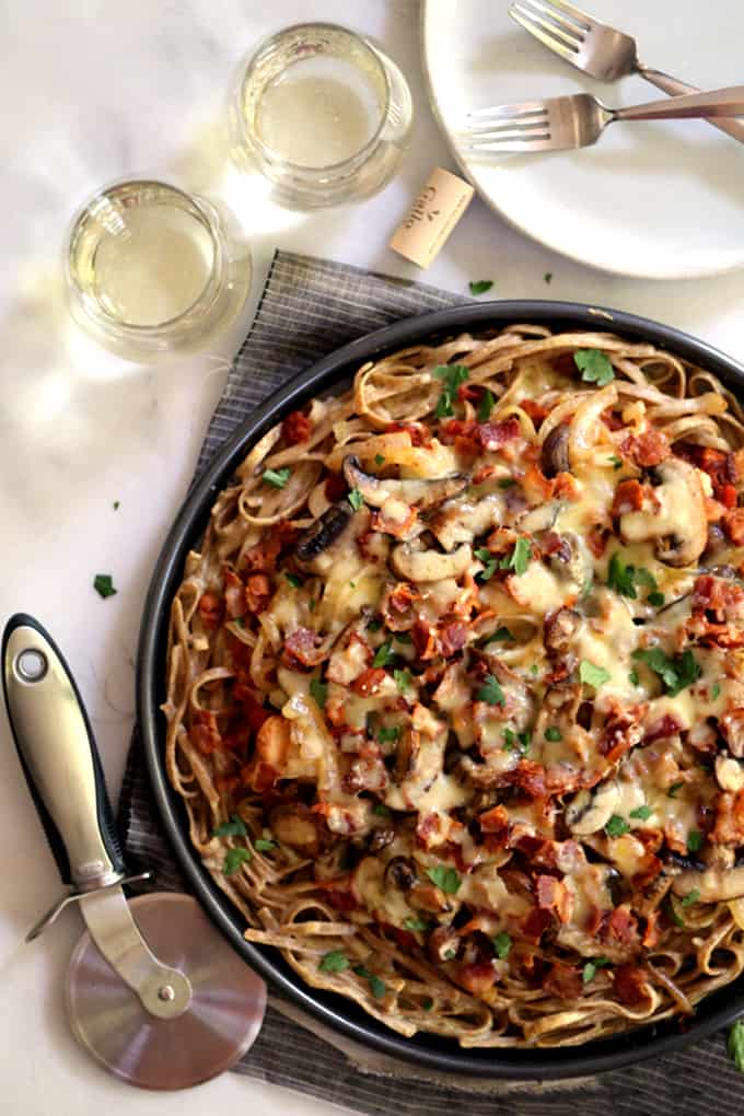 This Chicken Bacon Swiss Spaghetti Pizza is perfect for a night in or a night with friends.  A pasta crust spiked with Swiss cheese is the base of this masterpiece. Topped with bacon, chicken, mushrooms and onions which have all been cooked in rendered bacon fat, the entire pie is sprinkled with a generous amount of even more Swiss cheese.