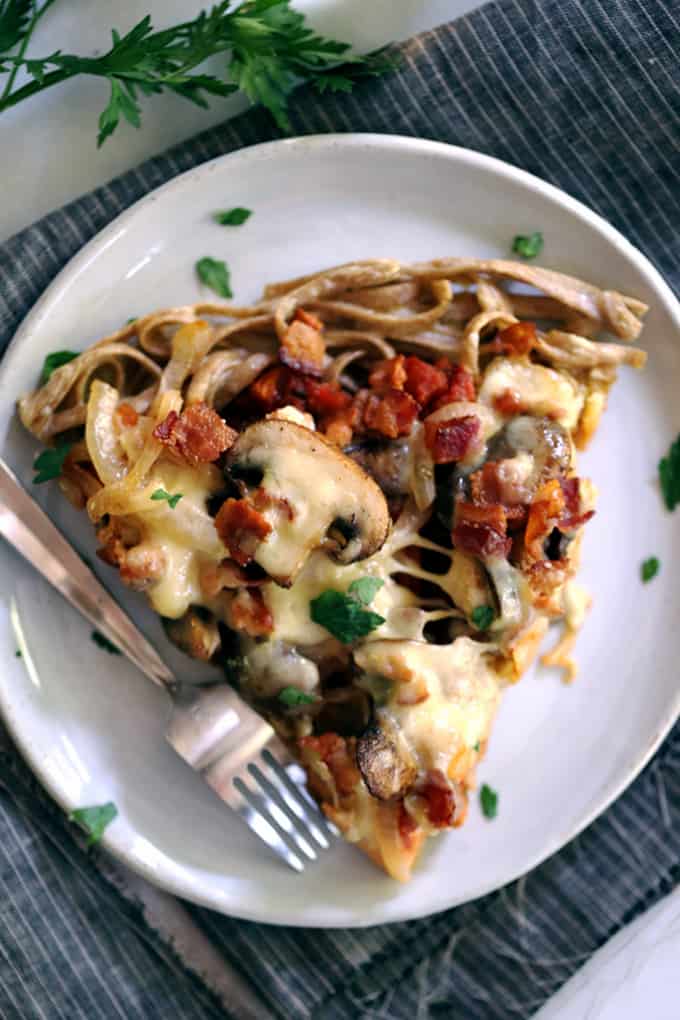 This Chicken Bacon Swiss Spaghetti Pizza is perfect for a night in or a night with friends.  A pasta crust spiked with Swiss cheese is the base of this masterpiece. Topped with bacon, chicken, mushrooms and onions which have all been cooked in rendered bacon fat, the entire pie is sprinkled with a generous amount of even more Swiss cheese.