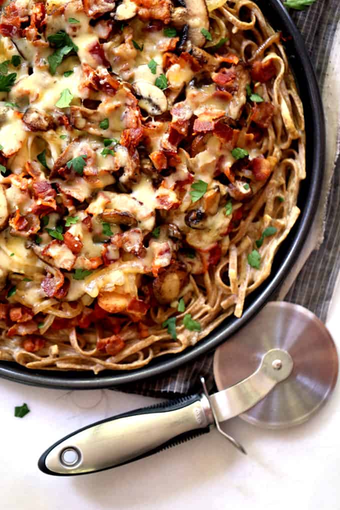 This Chicken Bacon Swiss Spaghetti Pizza is perfect for a night in or a night with friends.  A pasta crust spiked with Swiss cheese is the base of this masterpiece. Topped with bacon, chicken, mushrooms and onions which have all been cooked in rendered bacon fat, the entire pie is sprinkled with a generous amount of even more Swiss cheese.