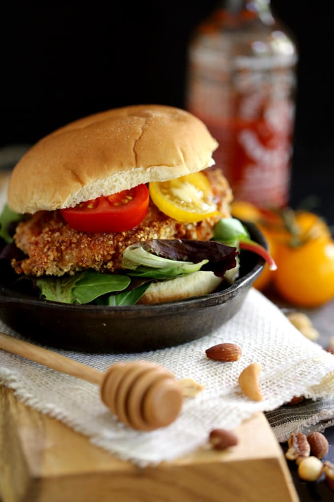 This seven ingredient Honey Sriracha Nut Oven Fried Chicken says so long to spattering oil and instead gets it's crispy crunch from an oven.  Marinated in buttermilk and coated in panko bread crumbs and mixed nuts before being bathed in a delicious honey Sriracha sauce, this chicken is the definition of sweet heat.