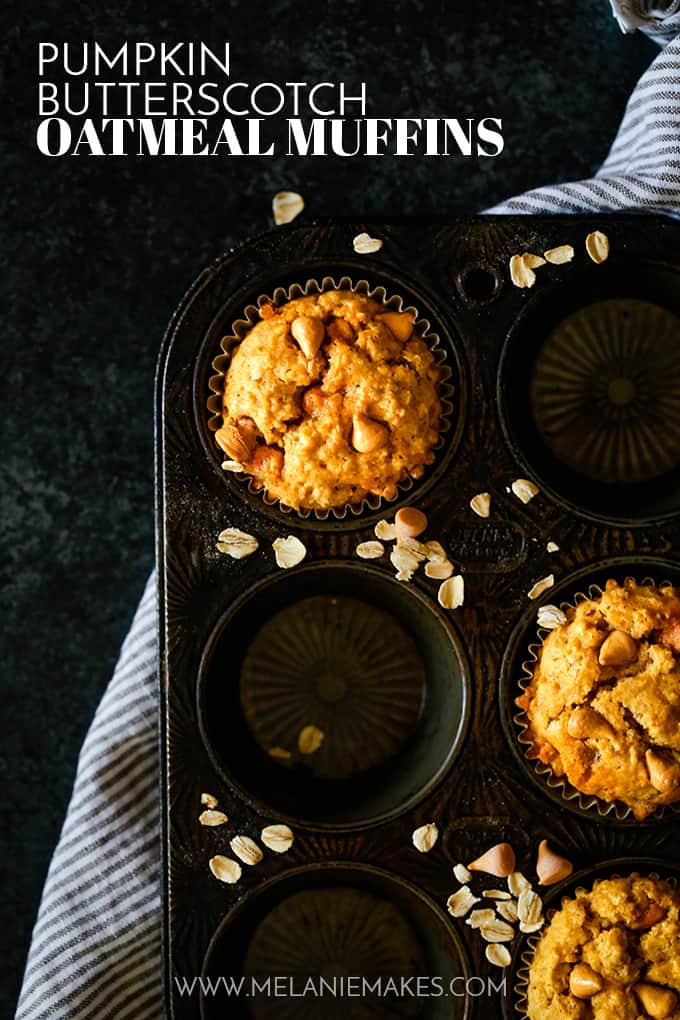 A muffin tin of three Pumpkin Butterscotch Oatmeal Muffins sits on a striped napkin on a dark background.