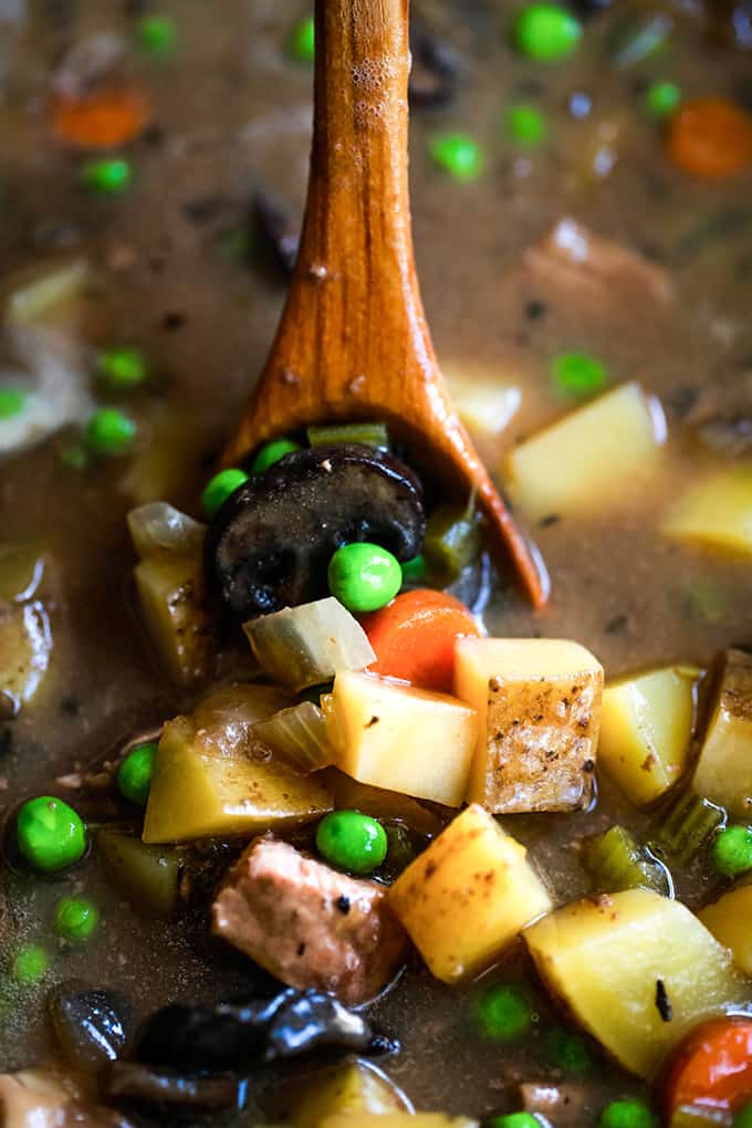 A wooden spoon in a bowl of Slow Cooker Beef and Guinness Pot Pie Soup.