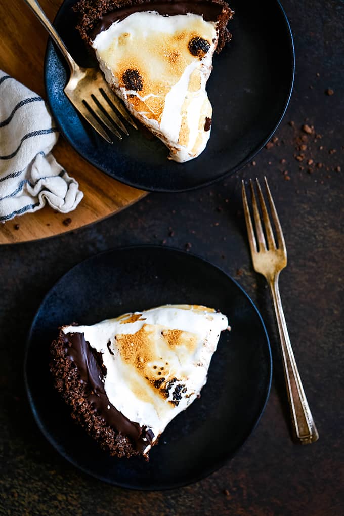 Slices of Double Chocolate No Bake S'mores Pie on black plates with forks.