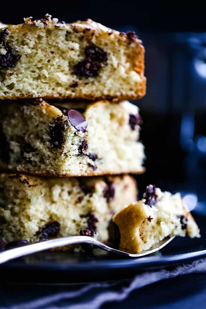 Three pieces of Chocolate Chip Sour Cream Coffee Cake stacked on a black plate with a fork.
