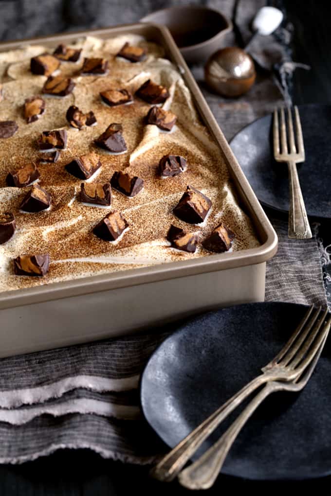 This Peanut Butter Mocha Poke cake is so decadent, so rich, and so incredibly easy! A mocha chocolate cake is flooded with peanut butter chocolate pudding before being topped with layers of mocha ganache, whipped topping and dark chocolate peanut butter cups before being dusted with espresso powder.