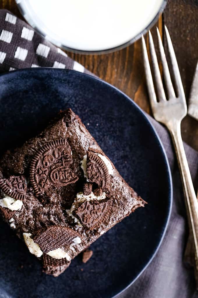 An overhead view of an Oreo Marshmallow Treat Brownie on a black plate with a fork on a grey napkin.