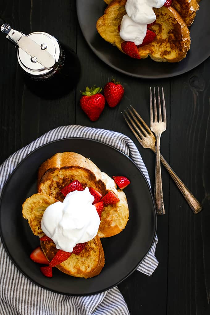 An overhead view of slices of Vanilla French Toast topped with strawberries and whipped cream.