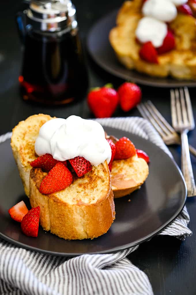 Slices of Vanilla French Toast on a plate on top of a striped napkin.