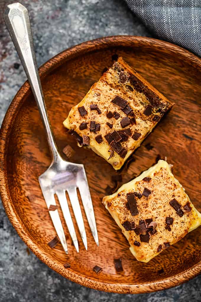 An overhead shot of two Chocolate Espresso Eggnog Bars sitting on a wooden plate with a fork.