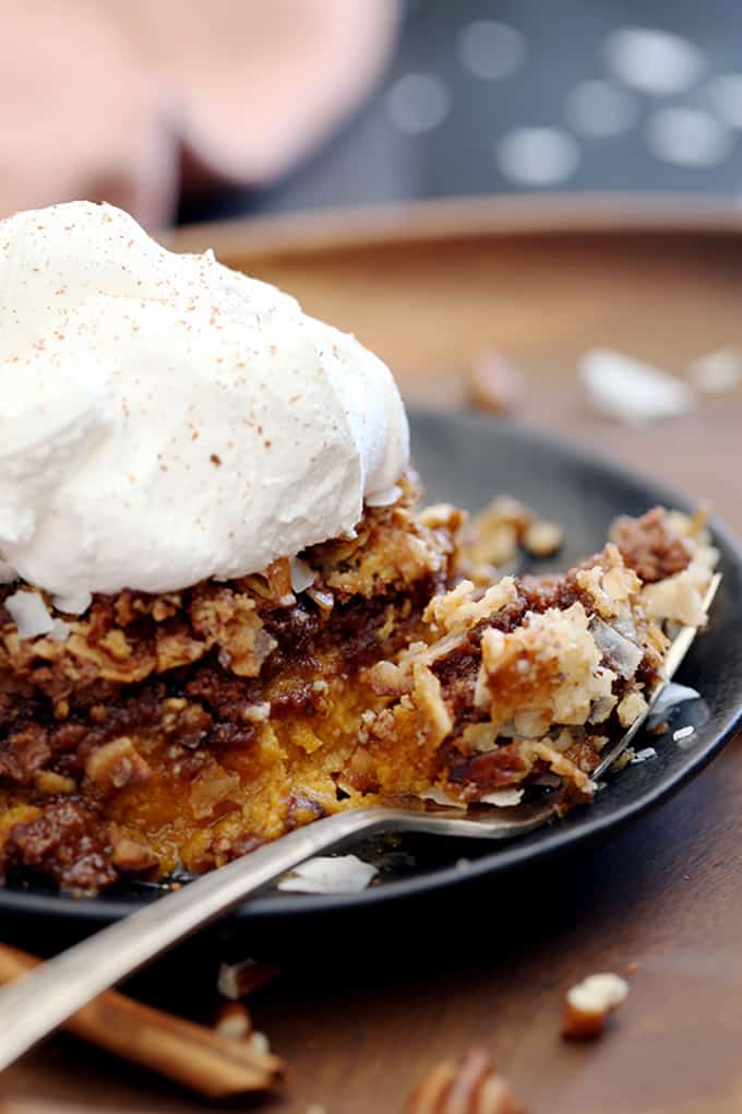 A fork with a bite of German Chocolate Upside Down Pumpkin Pie in front of a slice of the dessert.