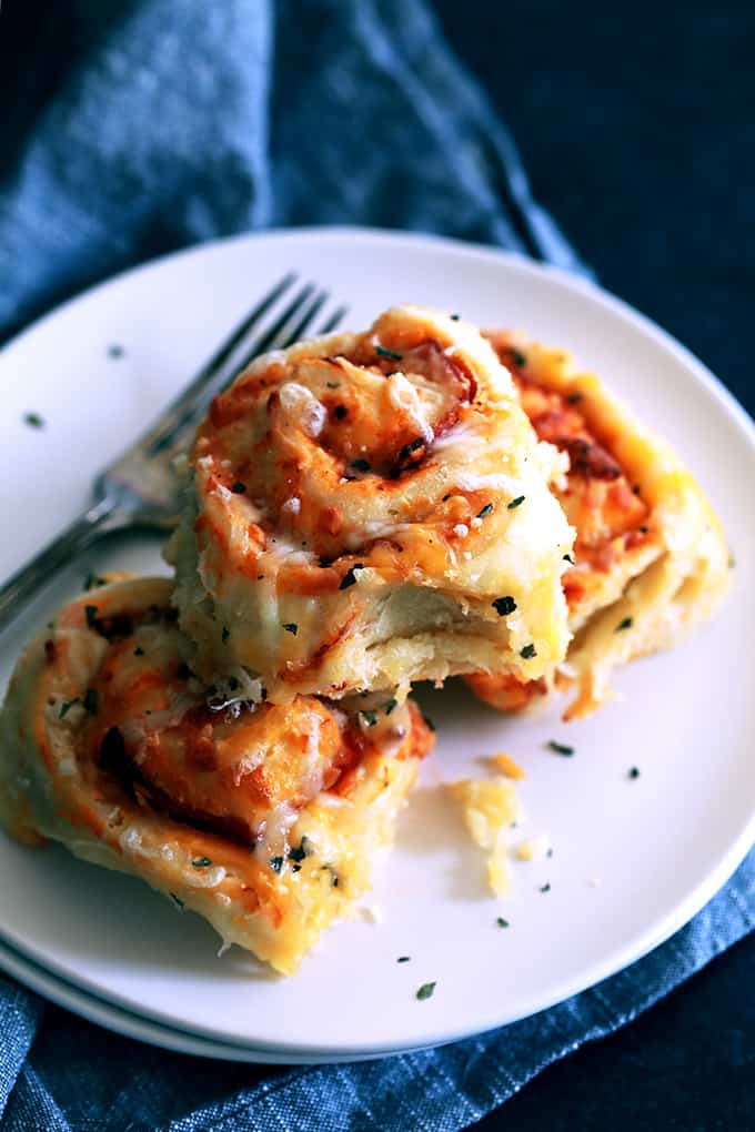 These Pepperoni Pizza Rolls are absolutely nothing like anything you can find in the grocery store freezer section. A fluffy, homemade brioche bread dough is layered with pizza sauce, garlic, pepperoni, mozzarella cheese and basil before being cut into rolls. After baking, they're sprinkled with even more cheese and basil to create these addictive rolls.