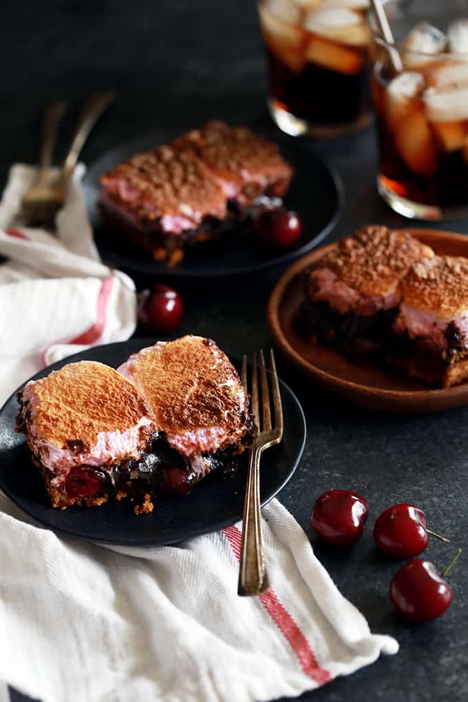 These Cherry Cola S'mores Brownies are the perfect dessert mashup. A buttery, graham cracker base is topped with a cherry cola spiked brownie batter, dark chocolate candy bars and maraschino cherries before being topped with a pillowy layer of cherry flavored marshmallows. They're pretty much heaven in brownie form!