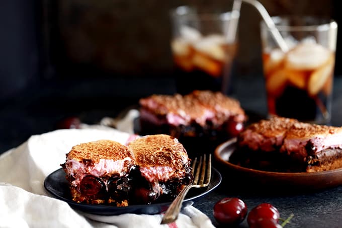 These Cherry Cola S'mores Brownies are the perfect dessert mashup. A buttery, graham cracker base is topped with a cherry cola spiked brownie batter, dark chocolate candy bars and maraschino cherries before being topped with a pillowy layer of cherry flavored marshmallows. They're pretty much heaven in brownie form!