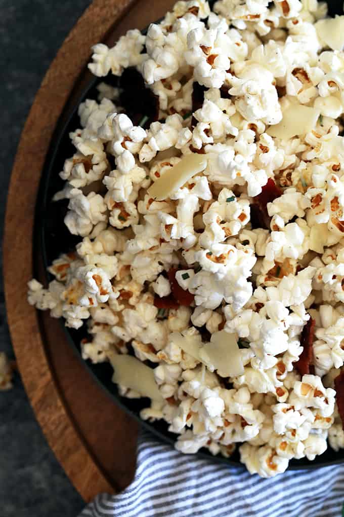 I've combined three of my favorite ingredients to make this Rosemary Parmesan Bacon Popcorn truly legendary.  Kernels of popcorn take a swim in bacon fat before popping and then tossed with fresh rosemary, shaved Parmesan cheese and crumbled bacon.  Perfect for movie night, game day or any time you need an amazing savory snack.