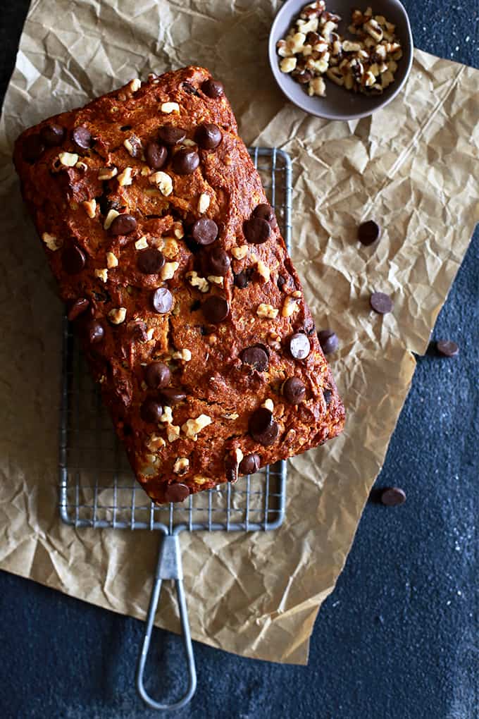 An overhead view of a loaf of Chocolate Chip Walnut Pumpkin Bread resting on a vintage wire rack.