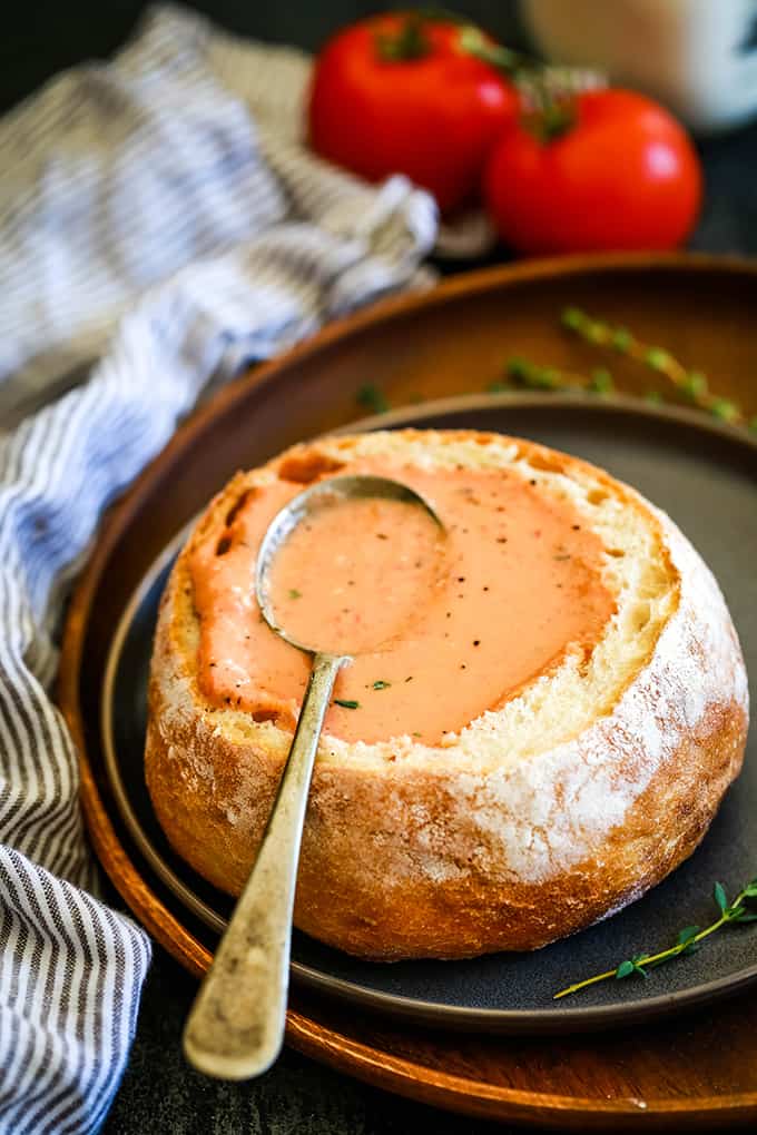 Creamy Tomato Bacon Soup in a bread bowl with a spoon.