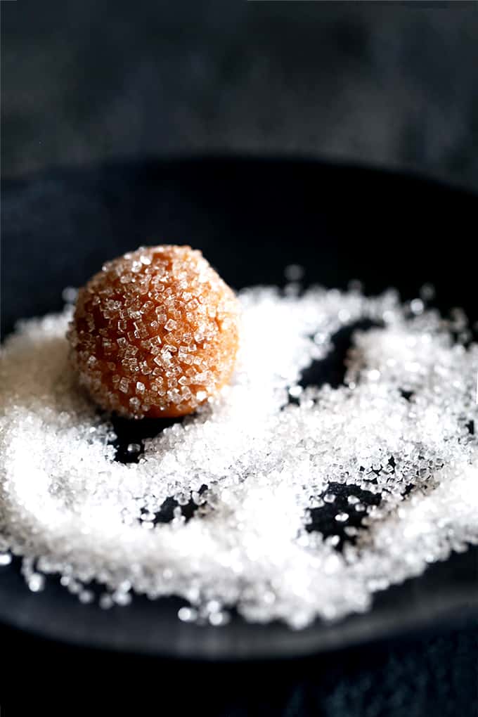 These eight ingredient Soft and Chewy Pumpkin Ginger Cookies are perfect any time of year but are destined to be an autumn cookie all-star. Pumpkin, molasses, cinnamon and ginger bring the warmth and expected fall flavors to these pillowy cookies. #pumpkin #ginger #cookies #autumn #fallrecipes #easydesserts A ball of Soft and Chewy Pumpkin Ginger Cookie dough rests in a plate full of sanding sugar.