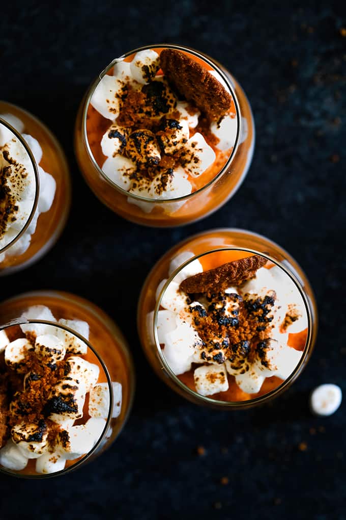 An overhead shot of four Gingersnap Sweet Potato Mousse desserts sitting on a dark surface.