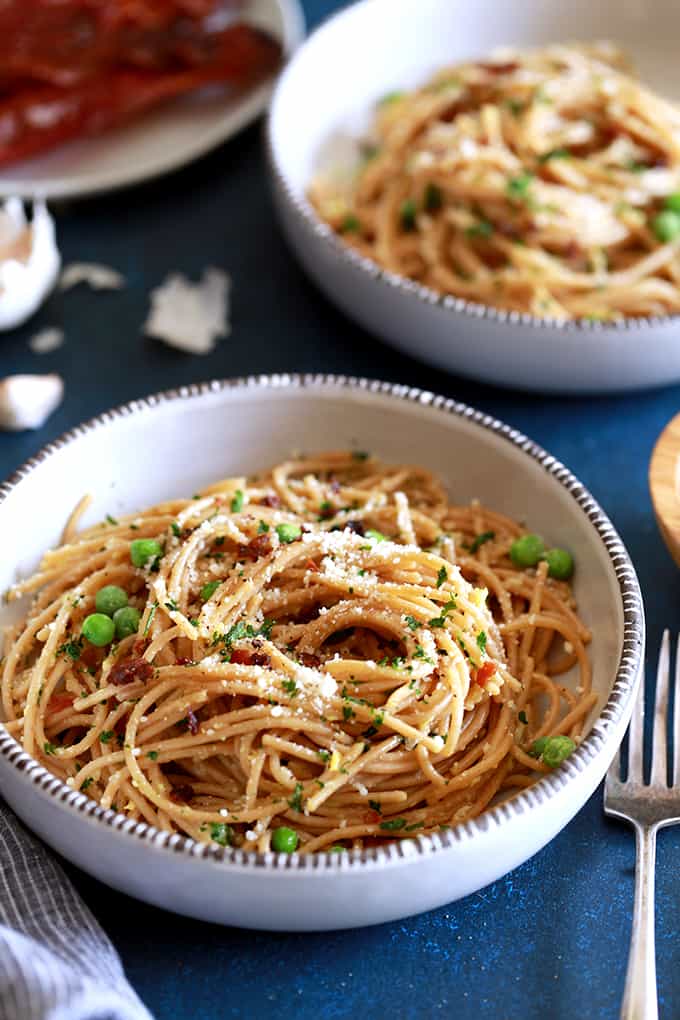 Pasta for breakfast?  This Breakfast Carbonara is absolutely a real and delicious thing!  Al dente spaghetti is tossed with minced garlic and peas before being swirled together with beaten eggs that are cooked by the heat from the hot pasta before being showered with grated Parmesan cheese and parsley as well as crumbled strips of bacon.   